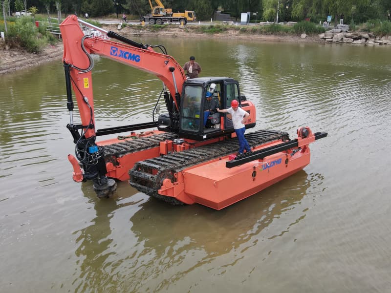 Mit Pontons ausgestatteter Amphibienbagger arbeitet im See/Fluss