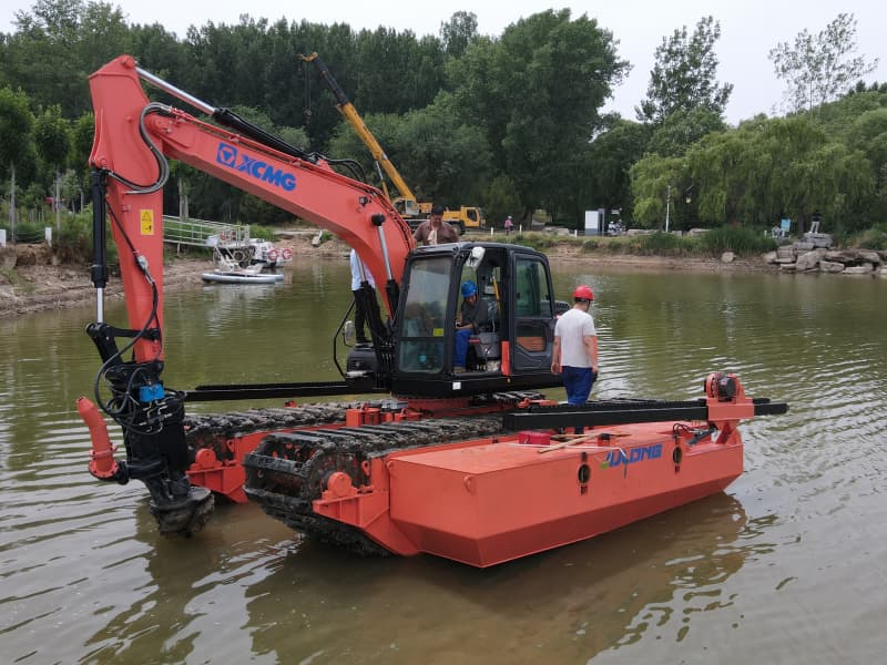 Mit Pontons ausgestatteter Amphibienbagger arbeitet im See/Fluss
